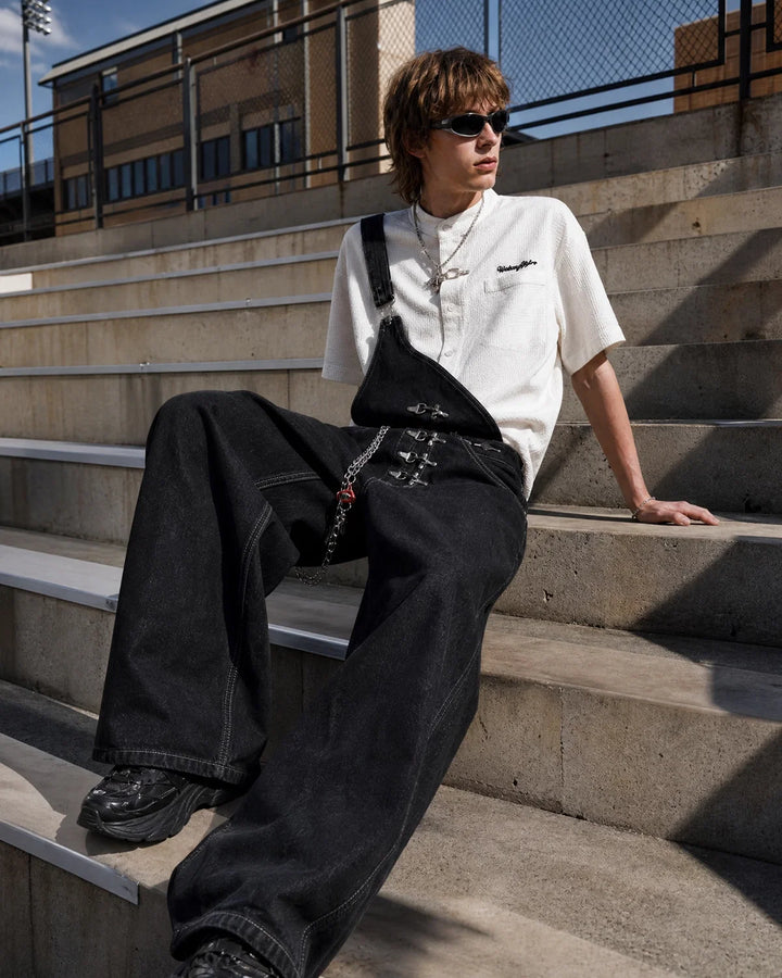 Black asymmetric denim overalls with buckle details and wide legs