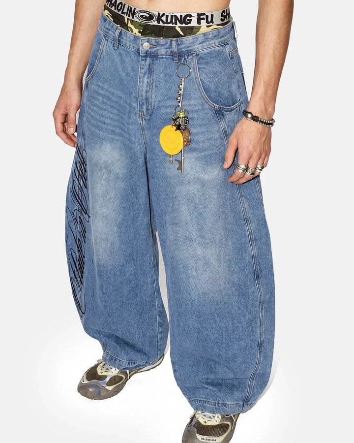Light blue barrel jeans with dark script graphic on one leg