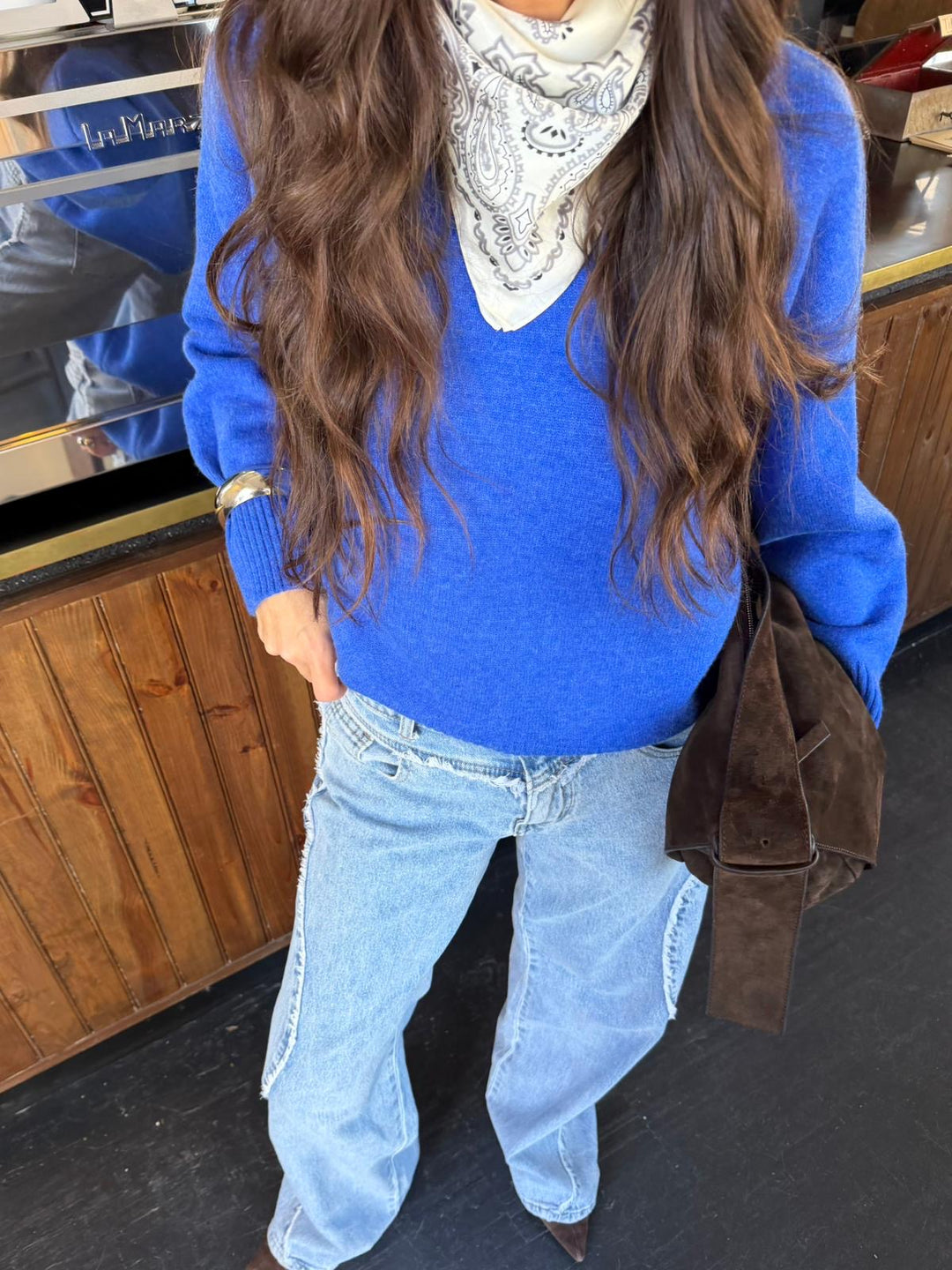 Woman wearing a blue V-neck knit sweater with long sleeves and ribbed trims
