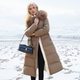 Women's longline quilted coat with fur-effect collar in a snowy outdoor setting