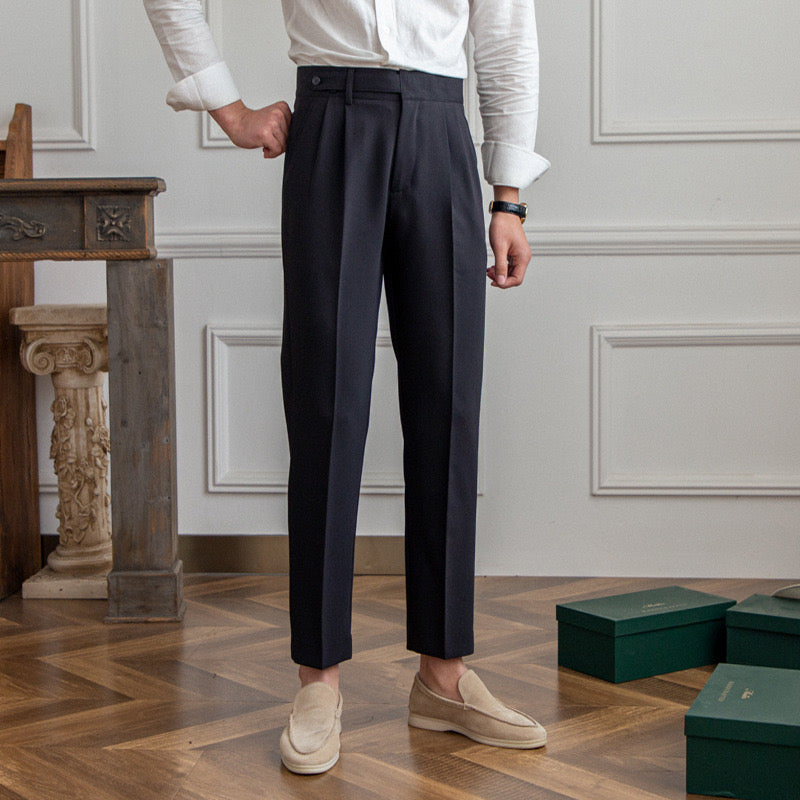 Woman wearing high-rise pleated tailored trousers in beige, cropped ankle length