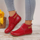 Women's rounded-toe ankle boots with side buckle strap in red, shown with light blue jeans.