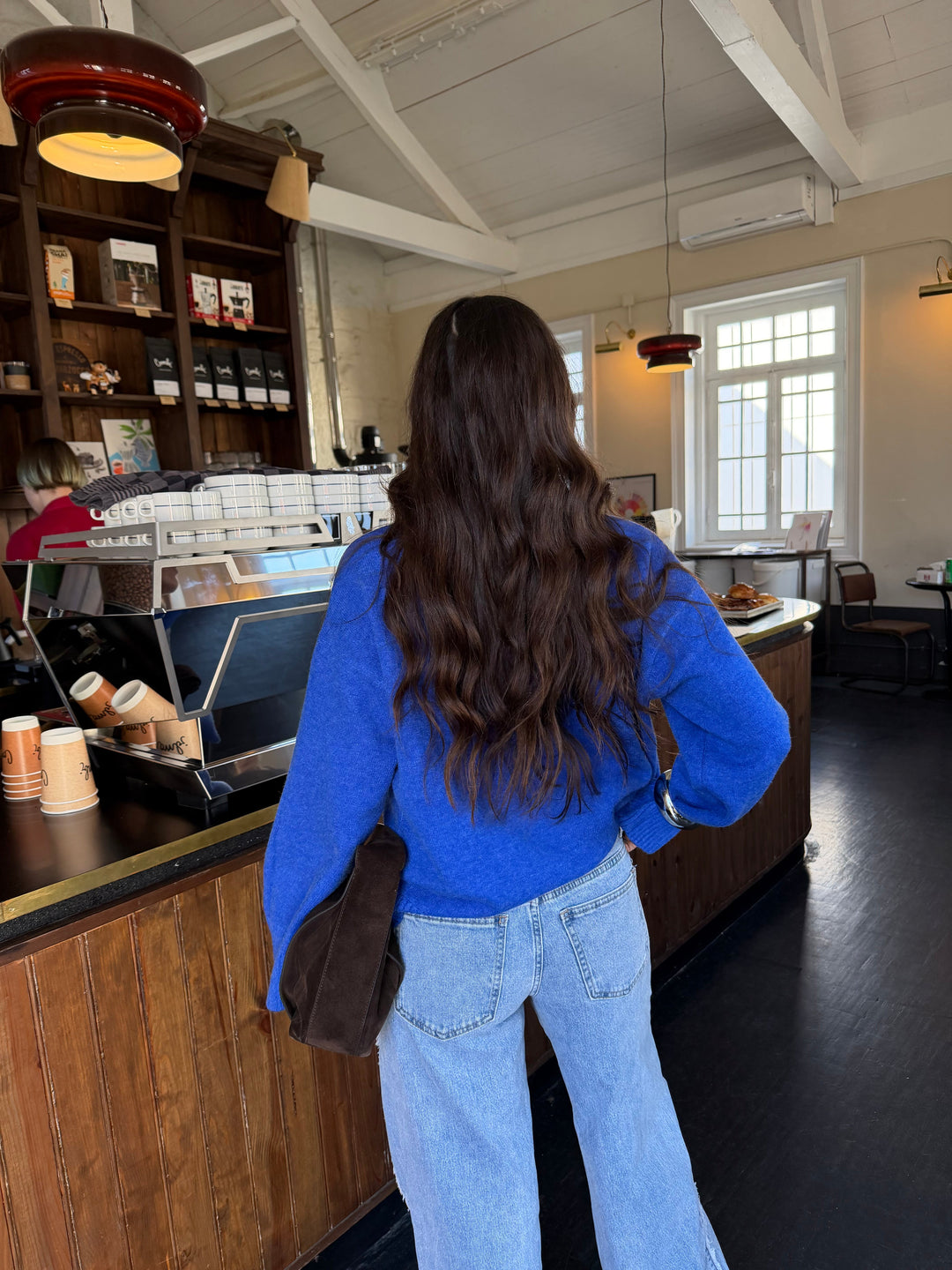 Woman wearing a blue V-neck knit sweater with long sleeves and ribbed trims