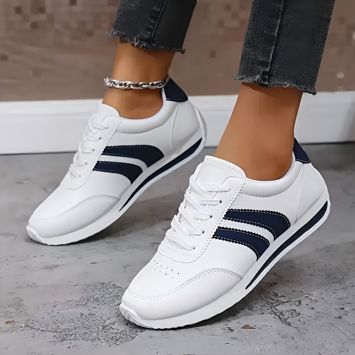 White lace-up trainers with navy side stripes and flat soles