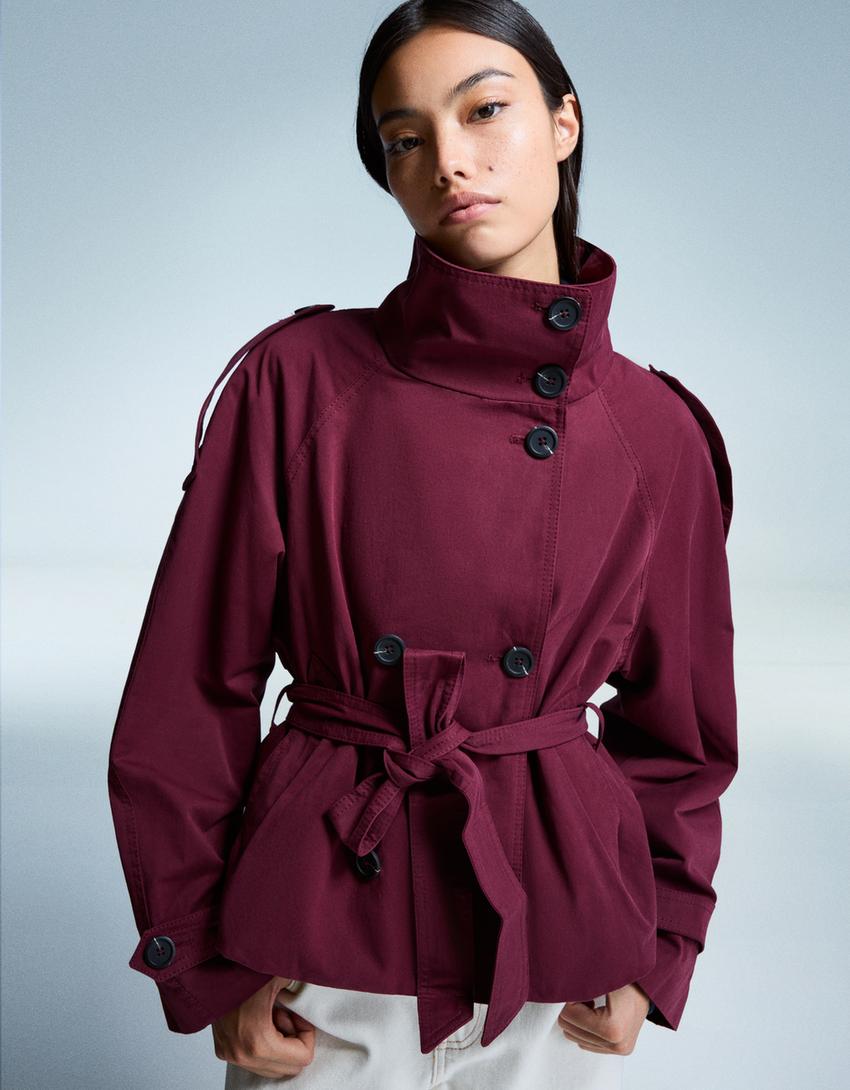 Women's short trench jacket with high collar, buttons, belt and shoulder tabs