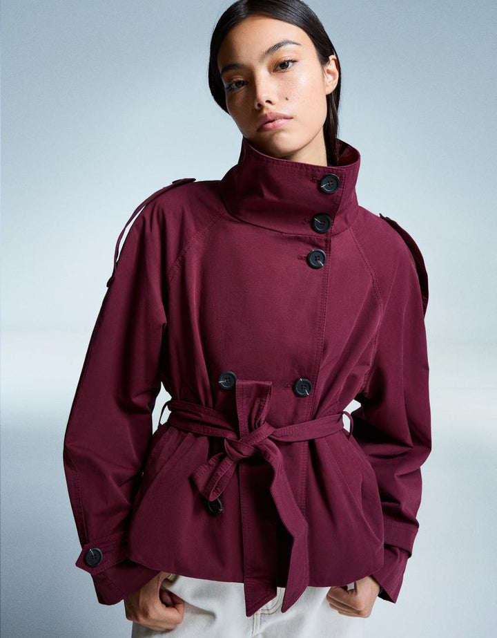 Women's short trench jacket with high collar, buttons, belt and shoulder tabs