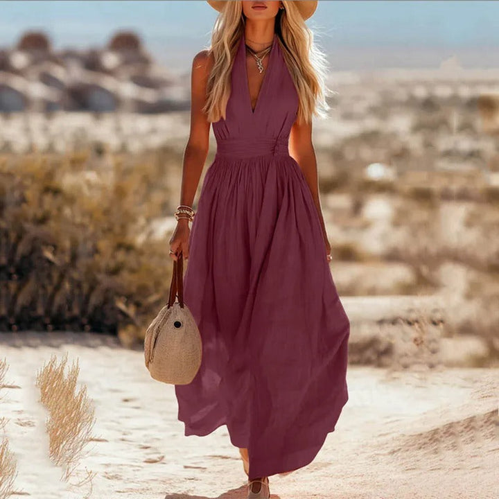 Women's halter maxi dress in brown and white with V-neck, sleeveless cut, and pleated skirt
