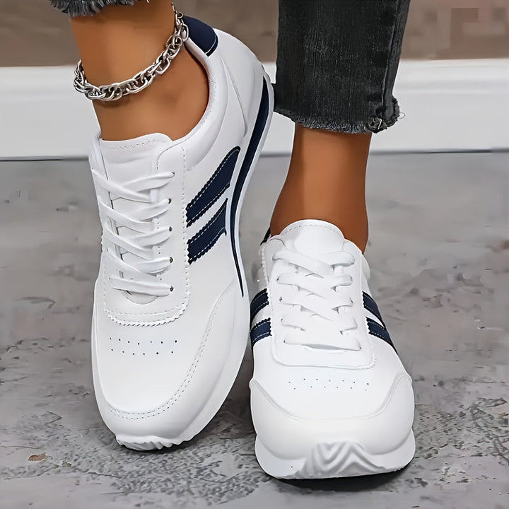 White lace-up trainers with navy side stripes and flat soles