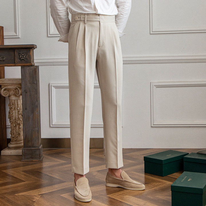 Woman wearing high-rise pleated tailored trousers in beige, cropped ankle length
