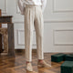 Woman wearing high-rise pleated tailored trousers in beige, cropped ankle length