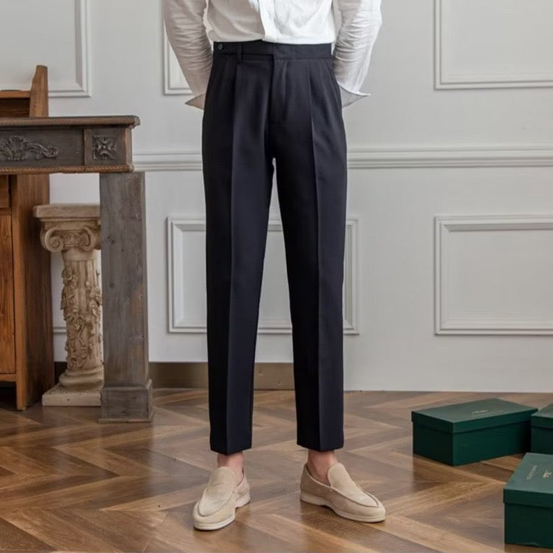 Woman wearing high-rise pleated tailored trousers in beige, cropped ankle length