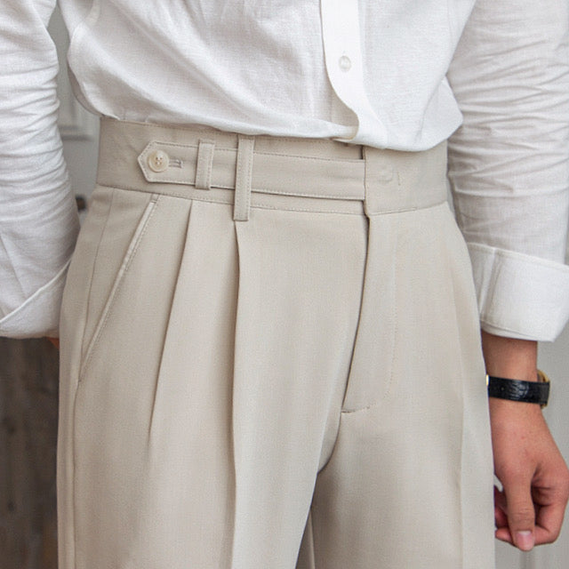 Woman wearing high-rise pleated tailored trousers in beige, cropped ankle length