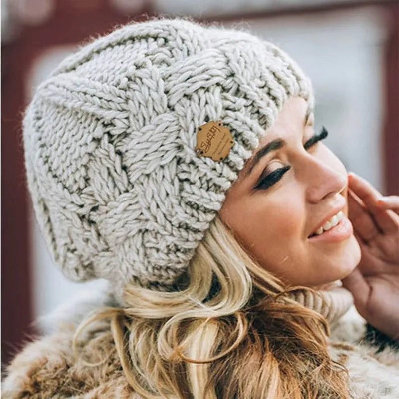 Women's chunky cable knit beanie hat with folded cuff and front badge