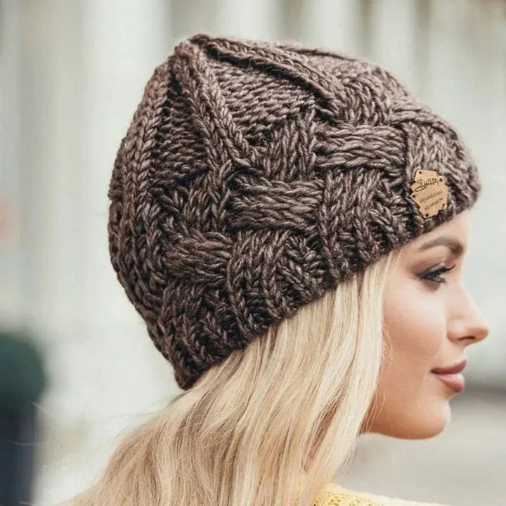 Women's chunky cable knit beanie hat with folded cuff and front badge