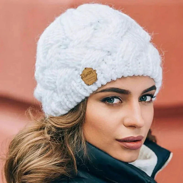 Women's chunky cable knit beanie hat with folded cuff and front badge