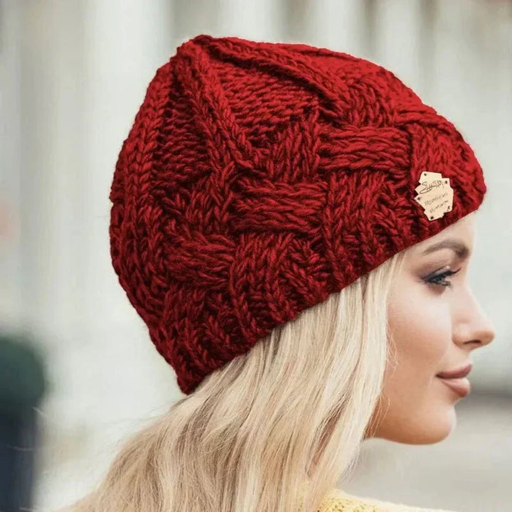 Women's chunky cable knit beanie hat with folded cuff and front badge
