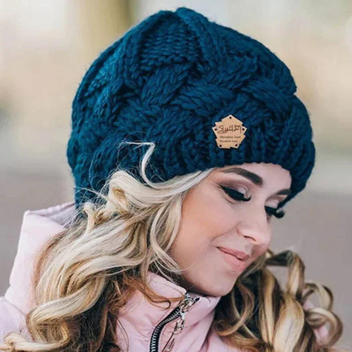 Women's chunky cable knit beanie hat with folded cuff and front badge