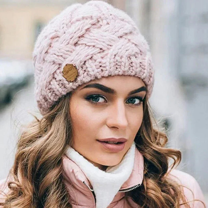 Women's chunky cable knit beanie hat with folded cuff and front badge