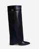 Women's black knee-high boots with pointed toes, low heels and buckle straps