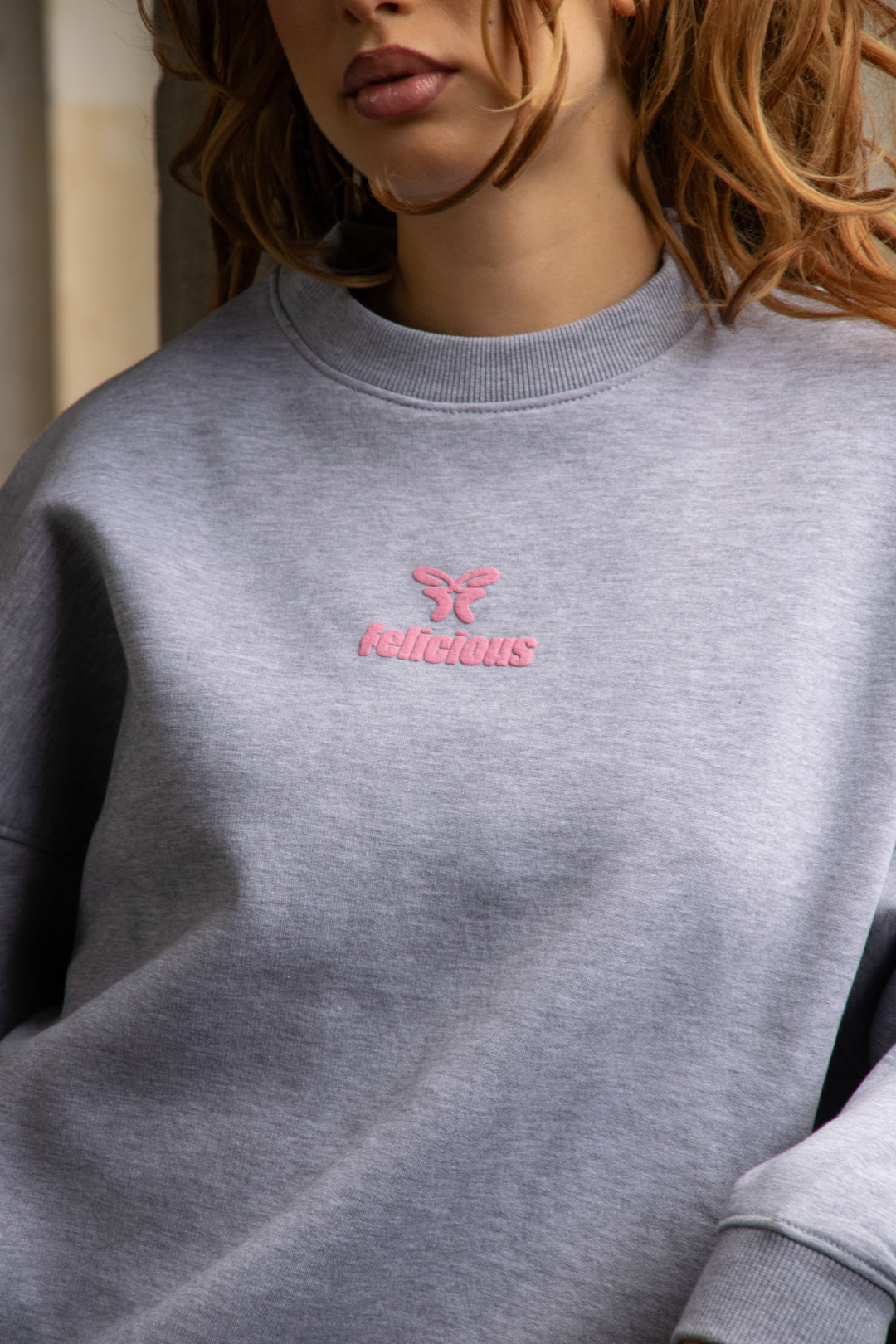 Women's light grey crewneck sweatshirt with pink chest logo and long sleeves