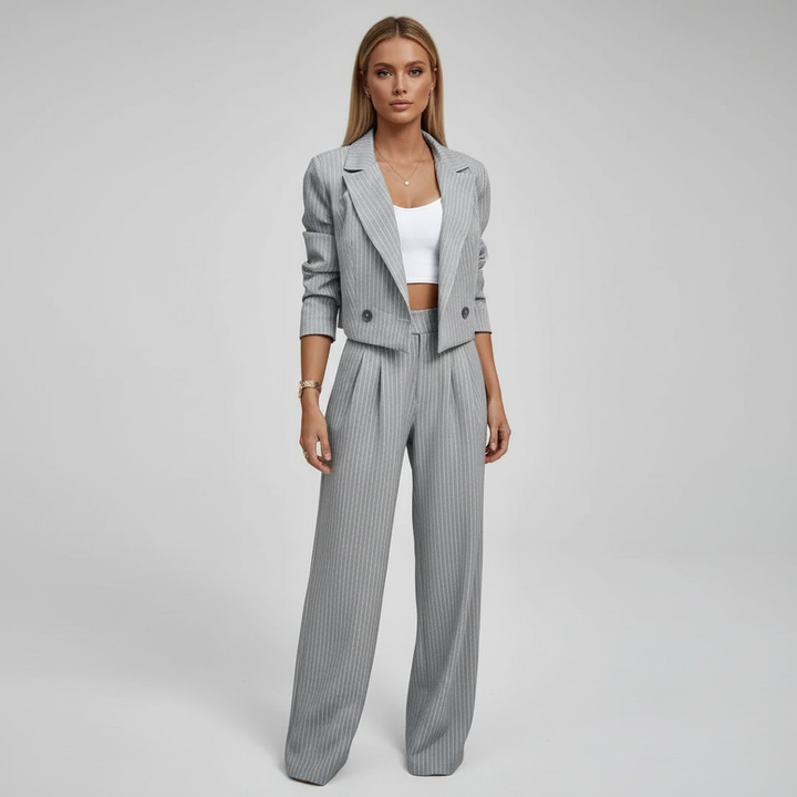 Women's pinstripe trouser suit in navy and grey, shown on two models with white crop top and white trainers.