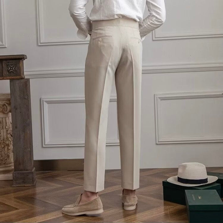 Woman wearing high-rise pleated tailored trousers in beige, cropped ankle length