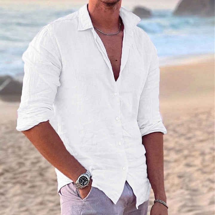 Men's long sleeve button-front shirt in white and black, shown on beach, worn open with relaxed fit.
