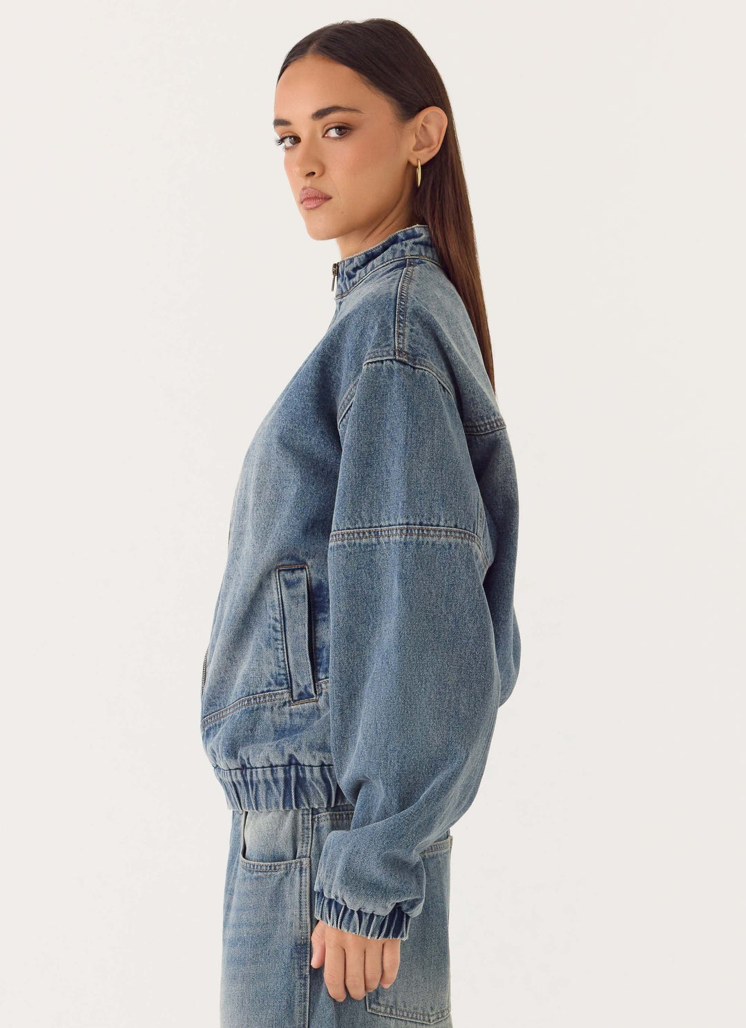 Women's mid-wash blue denim bomber jacket with high collar and zip front