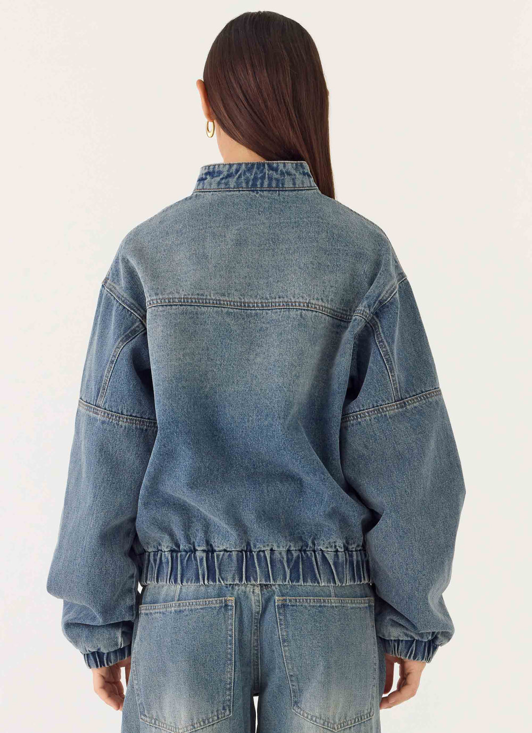 Women's mid-wash blue denim bomber jacket with high collar and zip front