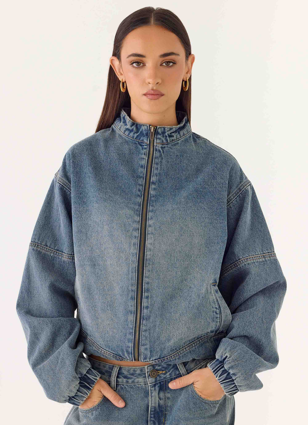 Women's mid-wash blue denim bomber jacket with high collar and zip front