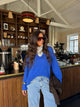 Woman wearing a blue V-neck knit sweater with long sleeves and ribbed trims