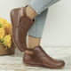 Women's rounded-toe ankle boots with side buckle strap in red, shown with light blue jeans.